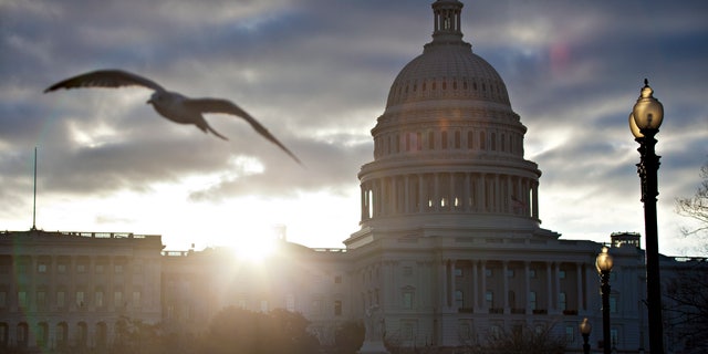 FILE -- At dawn, the sun breaks through dark clouds over Capitol Hill in Washington.