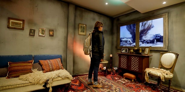 A woman watches a video of an explosion as she stands inside a mock-up Syrian home, set up by Amnesty International inside a subway station, in Buenos Aires, Argentina, Monday, Sept. 19, 2016.