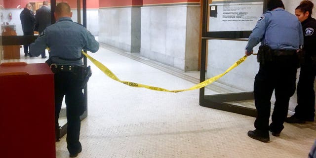 Police set up crime scene tape outside a Minneapolis police room at Minneapolis City Hall on Monday, Dec. 18, 2017. Minneapolis police say their officers have been involved in a shooting inside the department's investigative unit at City Hall. (AP Photo/Jeff Baenen)
