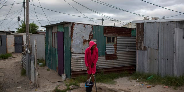 In this Feb. 2, 2018 photo, a woman collects water in a settlement near South Africa's drought-hit city of Cape Town. About a quarter of Cape Town's population lives in the informal settlements, where they get water from communal taps instead of individual taps at home like in the richer suburbs.