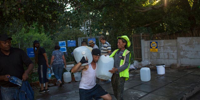 Two men help each other carry water at a source for natural spring water in Cape Town. Cape Town residents are allowed to use no more than 50 liters of water daily. Authorities say they might have to turn off most city taps in May if residents don't save enough water in what they call "Day Zero."