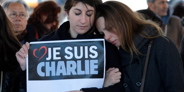 People pay tribute to the victims of the satirical newspaper "Charlie Hebdo", in Marseille, southern France, Thursday, Jan. 8, 2015, a day after masked gunmen stormed the offices of a satirical newspaper and killed 12 people. French police hunted Thursday for two heavily armed men one with a terrorism conviction and a history in jihadi networks in the methodical killing of 12 people at a satirical newspaper that caricatured the Prophet Muhammad. Placard reads "I am Charlie" . (AP Photo/Claude Paris)