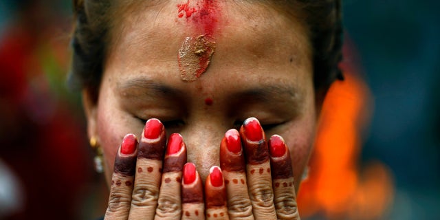 A Nepalese Hindu woman offers prayers at the Pashupatinath temple during Teej festival celebrations in Katmandu, Nepal, Tuesday, Sept. 18, 2012. (AP Photo/Niranjan Shrestha)