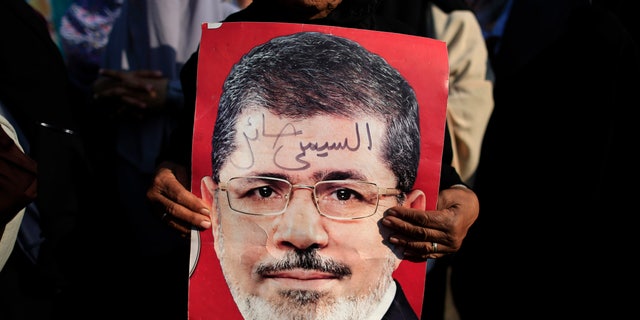 A supporter holds a poster of Egypt's Islamist President Mohammed Morsi with Arabic that reads, "Sisi traitor," during a rally, in Nasser City, Cairo, Egypt, July 4, 2013.