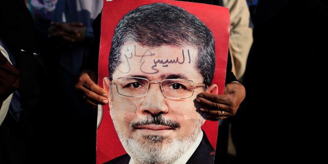 A supporter holds a poster of Egypt's Islamist President Mohammed Morsi with Arabic that reads, "Sisi traitor," during a rally, in Nasser City, Cairo, Egypt, July 4, 2013.