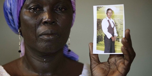 In this photo taken on Monday, May 19, 2014. Martha Mark, the mother of kidnapped school girl Monica Mark cries as she display her photo, in the family house, in Chibok, Nigeria. More than 200 schoolgirls were kidnapped from a school in Chibok in Nigeria's north-eastern state of Borno on April 14. Boko Haram claimed responsibility for the act. (AP Photo/Sunday Alamba)