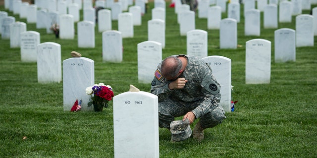 FILE -- Army Col. Matthew Rasmussen, of the Army Military District of Washington, wipes tears from his eyes while visiting the grave of Army Staff Sgt. Richard Tieman, 28, of Waynesboro, Pa.