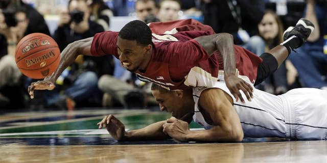 Florida State's Okaro White, top, falls over Virginia's Malcolm Brogdon, bottom, as they chase a loose ball during the second half of an NCAA college basketball game in the quarterfinal round of the Atlantic Coast Conference tournament in Greensboro, N.C., Friday, March 14, 2014. (AP Photo/Gerry Broome)