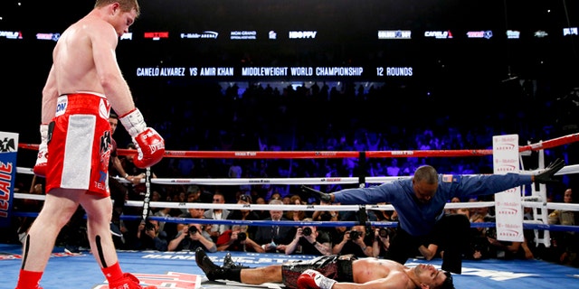 Canelo Alvarez, left, watches after knocking down Amir Khan during their WBC middleweight title fight Saturday, May 7, 2016, in Las Vegas. (AP Photo/John Locher)