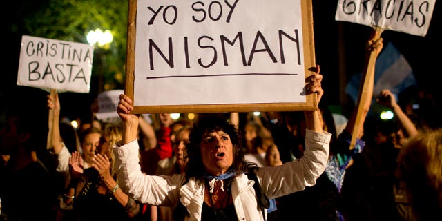 A demonstrator holds a sign that reads in Spanish "I am Nisman" during a protest sparked by the death of special prosecutor Alberto Nisman, outside the government house in Plaza de Mayo in Buenos Aires, Argentina, Monday, Jan. 19, 2015. The other signs read "Enough Cristina," left, and "Thank you Nisman." Nisman, who had been investigating the 1994 bombing of the AMIA Jewish community center in Buenos Aires that killed 85 people and who accused President Cristina Fernandez of shielding Iranian suspects, was found dead with a gunshot to his head in the bathroom of his apartment late Sunday, hours before he was to testify in a Congressional hearing about the case. (AP Photo/Rodrigo Abd)