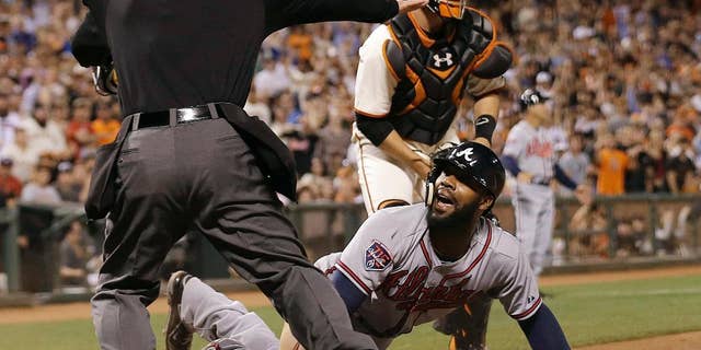 Atlanta Braves' Jason Heyward, bottom, is called safe at home by umpire Ed Hickox, left, in front of San Francisco Giants catcher Buster Posey during the sixth inning of a baseball game in San Francisco, Tuesday, May 13, 2014. Giants manager Bruce Bochy challenged the ruling but the play stood. The Braves won 5-0. (AP Photo)