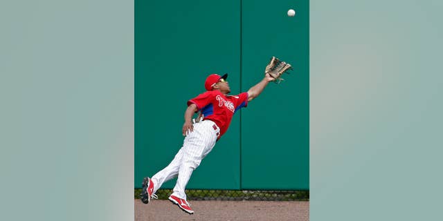 Philadelphia Phillies center fielder Ben Revere (2) dives for Atlanta Braves Gerald Laird's fourth-inning double in a spring exhibition baseball game in Clearwater, Fla., Monday, March 10, 2014.  (AP Photo/Kathy Willens)
