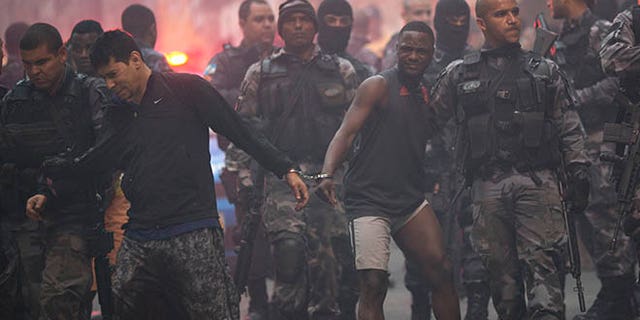 Police move a couple of handcuffed, recently detained men in Rio de Janeiro, Brazil, Monday, Oct. 10, 2016.
