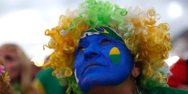 A fan of the Brazil national soccer team watches a live broadcast of the World Cup third-place soccer match between Brazil and Netherlands, inside the FIFA Fan Fest area on Copacabana beach, in Rio de Janeiro, Brazil, Saturday, July 12, 2014. (AP Photo/Silvia Izquierdo)