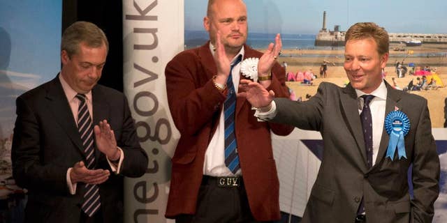 The Conservative Party's Craig Mackinlay, right, waves after winning the count for the South Thanet seat beside, from left, Nigel Farage the leader of the UK Independence Party (UKIP) and Al Murray a comedian who performs as "The Pub Landlord" at the Winter Gardens in Margate, south east England, Friday, May 8, 2015. British Prime Minister David Cameron appeared poised to remain in power Friday, with early British election results and exit polls indicating his Conservatives had won a resounding victory and will return to 10 Downing Street in a stronger position than before. (AP Photo/Matt Dunham)