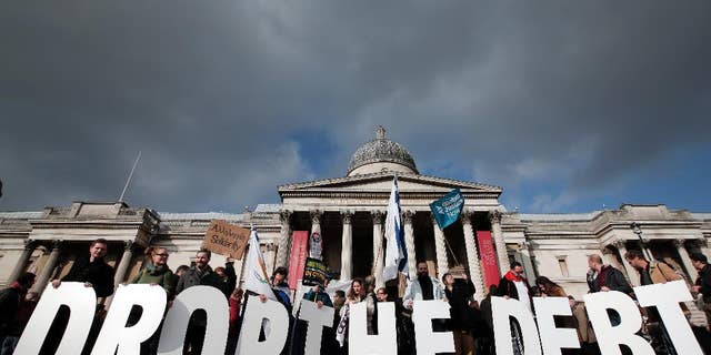 Protesters hold placards during a rally to show solidarity with Greece in central London, Sunday, Feb. 15, 2015. Hundreds of protesters gathered in support of the new government and the anti-austerity movement in Greece. Greece's new left-wing government is pressing for a short-term "bridge" agreement with eurozone lenders and a longer-term debt relief deal later this year. (AP Photo/Lefteris Pitarakis)