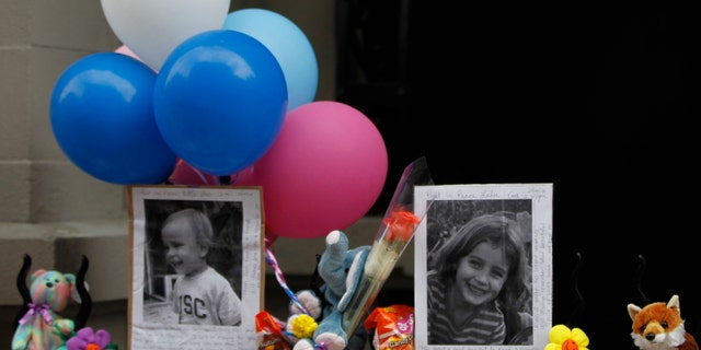 Photographs of the two children allegedly stabbed by their nanny are displayed alongside balloons and stuffed animals at a memorial outside the apartment building were they lived in New York.