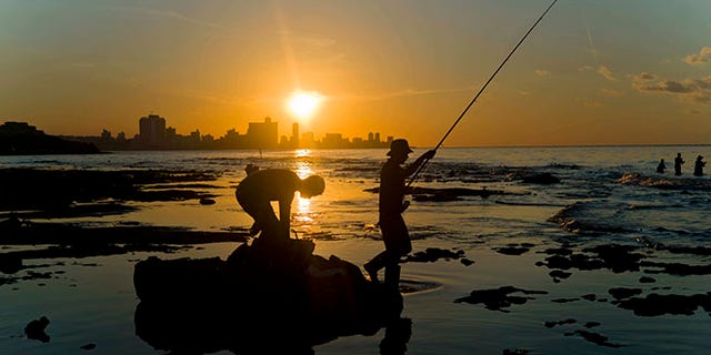 In this Nov. 11, 2016 photo, fishermen throw their fishing rods from Chivo beach as the sun sets in Havana, Cuba. Cuba has been renowned for its fishing at least since the days of Ernest Hemingway, and foreigners by the thousands come each year to fish in waters largely protected by Cubaâs lack of development. (AP Photo/Ramon Espinosa)