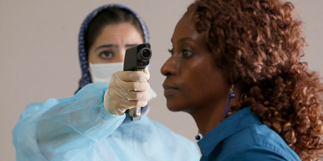 October 9, 2014: A Moroccan health worker uses a thermometer to screen a passenger at the arrivals hall of the Mohammed V airport in Casablanca. (AP Photo/The Canadian Press, Abdeljalil Bounhar)