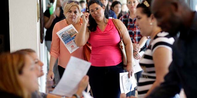 In this Tuesday, July 19, 2016, photo, Reina Borges, left, stands in line to apply for a job with Aldi at a job fair in Miami Lakes, Fla. On Friday, Aug. 5, the Labor Department issues its jobs report for July. (AP Photo/Lynne Sladky)