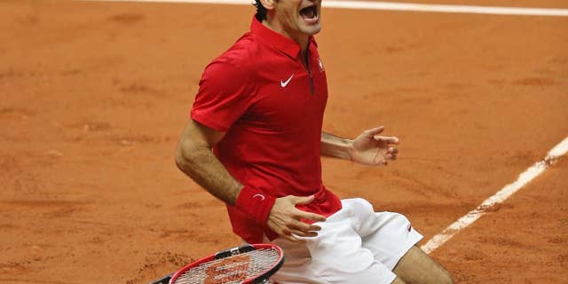 Switzerland's Roger Federer falls to the clay after defeating France's Richard Gasquet and winning the Davis Cup final between France and Switzerland at Stade Pierre Mauroy in Lille, northern France, Sunday, Nov. 23, 2014. (AP Photo/Peter Dejong)