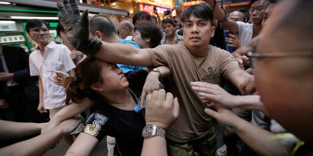 October 4, 2014: A woman is protected from the crowd by pro-democracy student protesters after a scuffle with local residents in Mong Kok, Hong Kong. Friction between pro-democracy protesters and opponents of their weeklong occupation of major Hong Kong streets persisted Saturday as police denied they had any connection to criminal gangs suspected of inciting attacks on largely peaceful demonstrators. (AP Photo/Wally Santana)