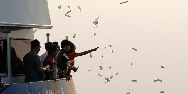 Oct. 2, 2012: Relatives of the victims throw paper money as they pay tribute to the ill-fated people aboard a boat that sank Monday night near Lamma Island, off the southwestern coast of Hong Kong Island.