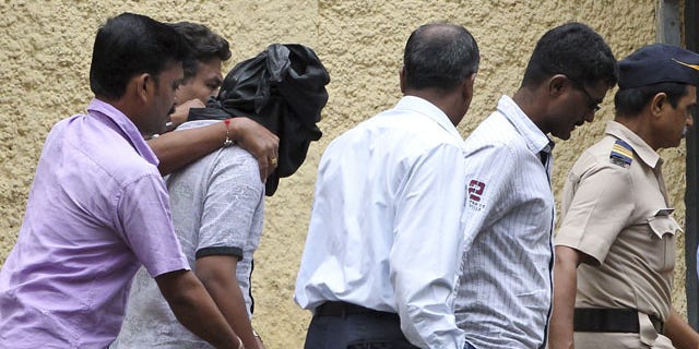 August 24, 2013: Police officials escort an accused, head covered with black cloth, in the gang rape of a young photojournalist in the Indian financial hub of Mumbai, India.