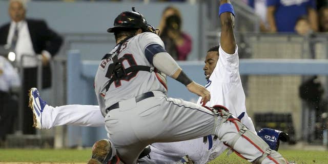 Los Angeles Dodgers' Dee Gordon, right, is tagged out at home by Cleveland Indians catcher Yan Gomes after Adrian Gonzalez lined into a triple play during the fourth inning of a baseball game in Los Angeles, Tuesday, July 1, 2014. (AP Photo/Chris Carlson)