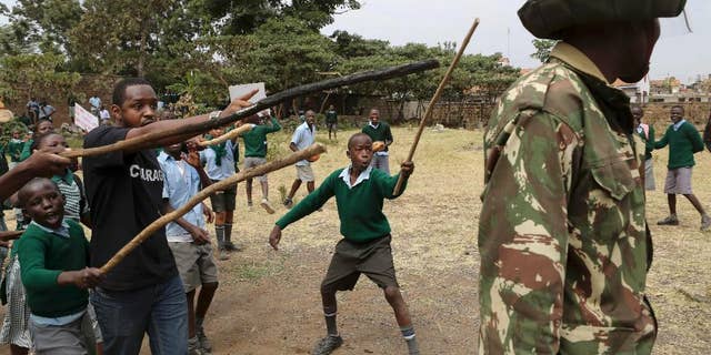 Kenyan school pupils and activists challenge riot police during a protest against the removal of their school's playground, at the Langata Road Primary School, in Nairobi, Kenya Monday, Jan. 19, 2015. Kenyan police tear-gassed schoolchildren demonstrating against the removal of their school's playground, the land of which has been allegedly grabbed by a powerful politician, according to a Kenyan human rights activist. (AP Photo/Brian Inganga)