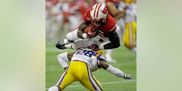 Wisconsin's Melvin Gordon leaps over LSU safety Jalen Mills (28) for a 14-yard touchdown run during the first half of an NCAA college football game Saturday, Aug. 30, 2014, in Houston. (AP Photo/David J. Phillip)