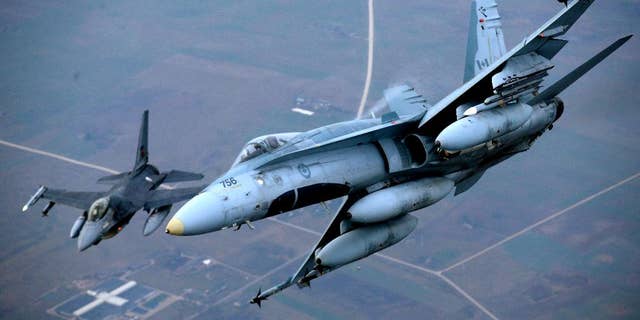 A Portuguese military fighter jet, left, and a Canadian military fighter jet participating in NATO's Baltic Air Policing Mission operate in Lithuanian airspace, Thursday, Nov. 20, 2014. NATO, which has 16 fighter jets in the region monitoring Baltic airspace, said it regularly launches jets to identify "unknown or potentially hostile aircraft" in the proximity of national airspace. (AP Photo/Mindaugas Kulbis)