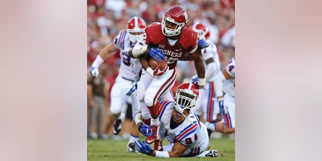 Oklahoma running back Samaje Perine (32) escapes a tackle attempt by Louisiana Tech defensive lineman Andre Taylor during the second quarter of an NCAA college football game in Norman, Okla., Saturday, Aug. 30, 2014. (AP Photo/Sue Ogrocki)