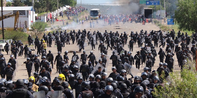 Riot police are forced to fall back as they battle with protesting teachers who were blocking a federal highway in the state of Oaxaca, near the town of Nochixtlan, Mexico, Sunday, June 19, 2016. The teachers are protesting against plans to overhaul the country's education system which include federally mandated teacher evaluations. (AP Photo/Luis Alberto Cruz Hernandez)