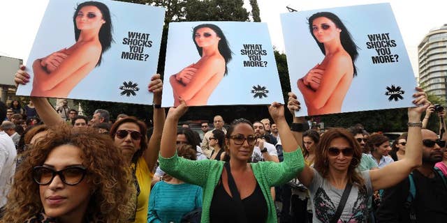 Lebanese women hold posters to mark International Woman's Day during a rally of thousands demanding that parliament approves a law that protects women from domestic violence, in Beirut, Lebanon, Saturday, March. 8, 2014. Although Lebanon appears very progressive on women rights compared to other countries in the Middle East, domestic violence remains an unspoken problem and the nation’s parliament has yet to vote on a bill protecting women’s rights nearly three years after it was approved by the Cabinet. (AP Photo/Bilal Hussein)