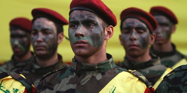 Hezbollah fighters stand by the coffin of senior Hezbollah commander Hassan Hussein al-Haj during his funeral procession in the southern Lebanese village of Loueizeh, Lebanon, Monday, Oct. 12, 2015. Local media said al-Haj was killed in the northwestern province of Idlib where Syrian government forces and Hezbollah fighters have launched an offensive against insurgents under the cover of Russian airstrikes. (AP Photo/Mohammed Zaatari)