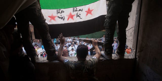 In this Friday, Sept. 21, 2012 photo, Free Syrian Army rebels hold a revolutionary flag on it during a demonstration in the Bustan al-Qasr neighborhood of Aleppo, Syria. The Britain-based Syrian Observatory for Human Rights said Friday that nearly 30,000 Syrians have been killed during the 18-month uprising against the Assad regime. Arabic on flag is reversed, but reads, "God welcome, free people." (AP Photo/ Manu Brabo)