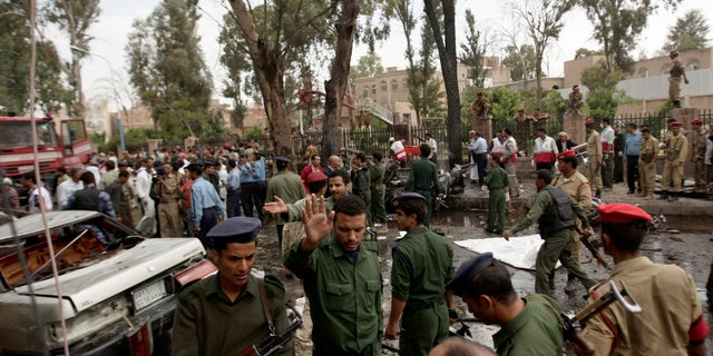 Yemeni officials and police gather at the site of a car bomb attack targeting the motorcade of the country's defense minister in Sanaa, Yemen, Tuesday, Sept. 11, 2012. Yemeni officials say a car bomb targeting the motorcade of the country's defense minister has killed several people, but the minister escaped unharmed. (AP Photo/Hani Mohammed)