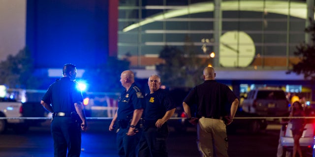 Law enforcement personnel stand near a police line at The Grand Theatre following a deadly shooting in Lafayette, La., Thursday, July 23, 2015. (Paul Kieu/The Daily Advertiser via AP)