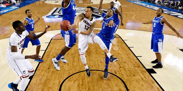 April 7, 2014: Connecticut guard Shabazz Napier (13) passes around Kentucky center Dakari Johnson (44) to center Amida Brimah (35) as guard James Young (1) helps during the first half of the NCAA Final Four tournament college basketball championship game in Arlington, Texas. (AP Photo/Chris Steppig, pool)