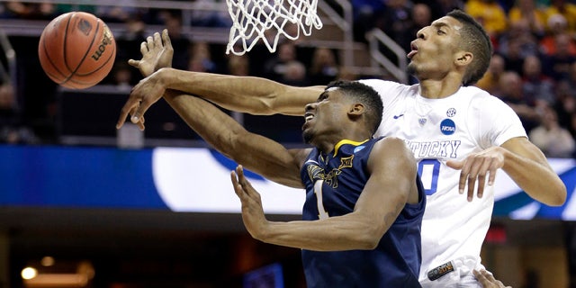 March 26, 2015: Kentucky's Marcus Lee, right, blocks a shot by West Virginia's Jonathan Holton during the first half of a college basketball game in the NCAA men's tournament regional semifinals in Cleveland. (AP Photo/Tony Dejak)