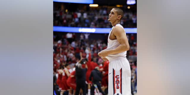Arizona's Nick Johnson reacts as Wisconsin celebrates after overtime in a regional final NCAA college basketball tournament game, Saturday, March 29, 2014, in Anaheim, Calif. Wisconsin won 64-63 in overtime. (AP Photo/Jae C. Hong)