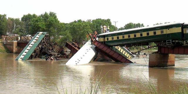 People gather during a rescue operation, after a bridge collapse led a train to fall into a canal in Wazirabad, near Lahore, Pakistan Thursday, July 2, 2015. At least four cars of a train being used to transport Pakistani soldiers fell into a canal because of a bridge collapse in the eastern Punjab province on Thursday, killing at least twelve soldiers, officials said. (AP Photo/Rameez Khan)