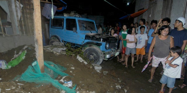 Residents gather at a collapsed house in Cagayan De Oro city, southern Philippines following a 7.6-magnitude earthquake that struck off the Philippines eastern coast late Friday Aug.31, 2012. The quake set off car alarms, shook items off shelves and sent many coastal residents fleeing for high ground before authorities lifted all tsunami warnings they had issued for the Philippines and neighboring countries from Indonesia to Japan, and for Pacific islands as far away as the Northern Marianas. (AP Photo/Froilan Gallardo)