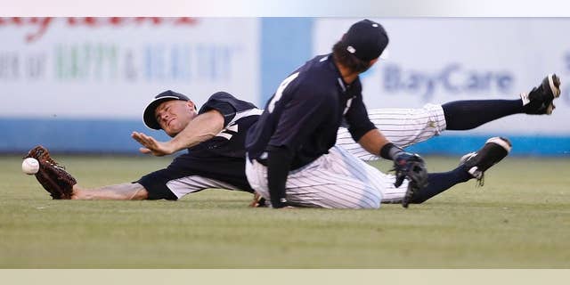 New York Yankees center fielder Brett Gardner loses the ball trying to catch a fly ball hit by Pittsburgh Pirates' Jordy Mercer while nearly colliding with Yankees second baseman Brian Roberts during the second inning of a spring exhibition baseball game against the Pittsburgh Pirates in Tampa, Fla., Friday, March 21, 2014. Mercer advanced to second on the play. (AP Photo/Kathy Willens)