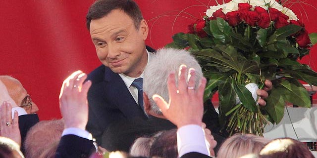 May 24, 2015: Opposition candidate Andrzej Duda celebrates with supporters as the first exit polls in the presidential runoff voting are announced in Warsaw. (AP Photo/Czarek Sokolowski)