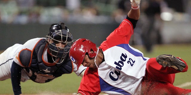 Cubaâs Yadiel Hernandez, right, slides safe at the home plate against Venezuela's catcher Jose Gil during a Caribbean Series baseball semifinal game in San Juan, Puerto Rico, Saturday, Feb. 7, 2015. (AP Photo/Ricardo Arduengo)