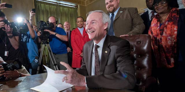 Arkansas Gov. Asa Hutchinson signs a reworked religious freedom bill into law after it passed in the House at the Arkansas state Capitol in Little Rock, Ark., Thursday, April 2, 2015. Lawmakers in Arkansas and Indiana passed legislation Thursday that they hoped would quiet the national uproar over new religious objections laws that opponents say are designed to offer a legal defense for anti-gay discrimination. (AP Photo/Brian Chilson)