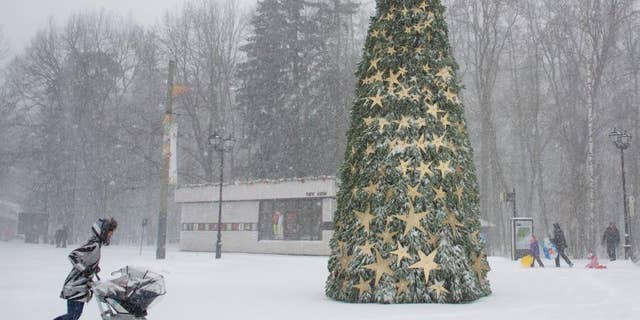 A woman walks with her child through heavy snowfall at a park in Moscow, Russia, Thursday, Dec. 25, 2014. (AP Photo/Ivan Sekretarev)