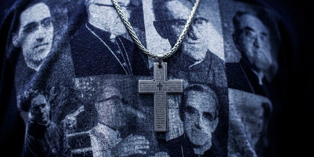 A man wears a cross and a T-shirt featuring portraits of Catholic Archbishop Oscar Romero during his beatification ceremony in San Salvador, El Salvador, Saturday, May 23, 2015. Romero was slain by an assassin's bullet 35 years ago and declared a martyr for his faith this year by Pope Francis. In life, Romero was loved by the poor, whom he defended passionately, and loathed by conservatives who considered him too close to left-leaning movements in the tumultuous years ahead of El Salvador's 1980-92 civil war. (AP Photo/Manu Brabo)